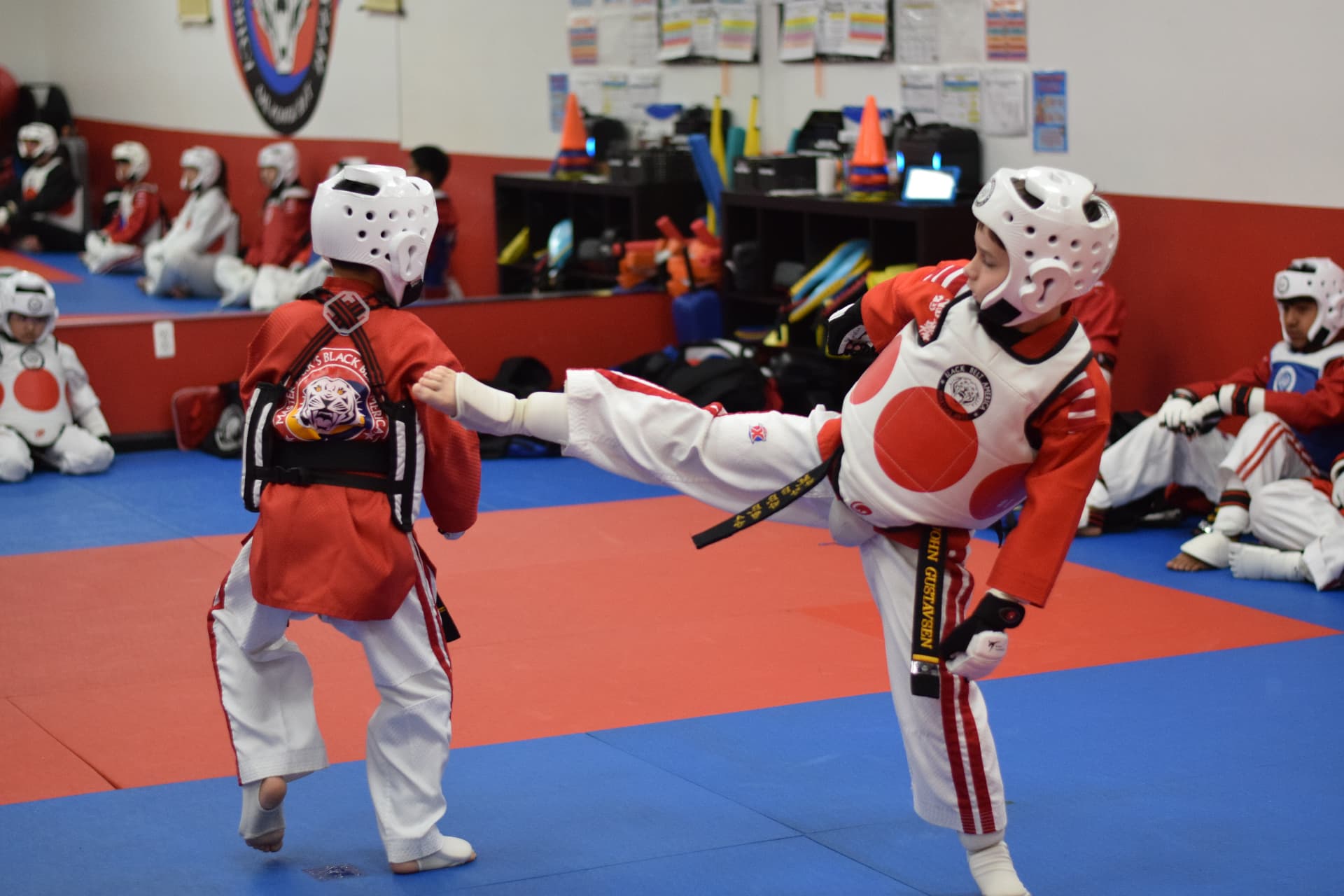 Two young students sparring in headgear and chest protectors at a Master Park's Black Belt America event